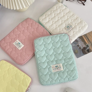 Detail of heart-quilted laptop sleeves in various pastel colors with fabric logo labels