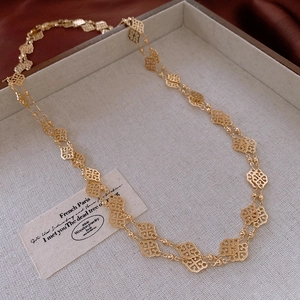 Detailed close-up of a gold hollow clover pattern necklace on a silk background