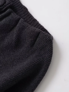 Gros plan sur la texture en maille côtelée gris foncé du manteau court en laine