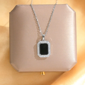Detailed view of silver necklace with rectangular black stone and pavé crystal halo on a jewelry box