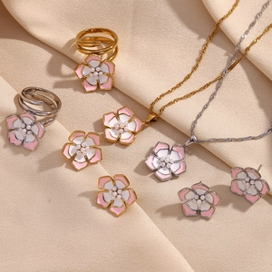 Floral jewelry set featuring pink and white enamel petals with pearls on soft fabric background