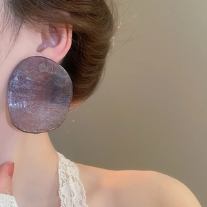 Macro detail of large translucent deep purple resin earring with brushed texture on model