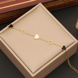 Gold double-layered necklace with black and white heart charms on a beige case