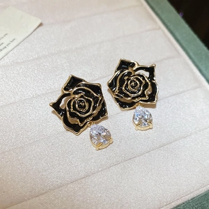 Close-up of black enamel rose earrings with pear-shaped cubic zirconia drops