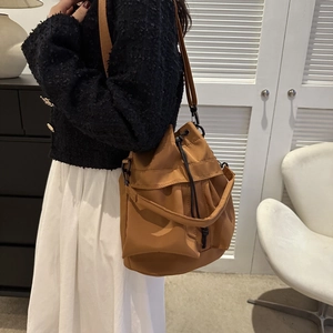 Sac seau marron à cordon porté à l'épaule par un mannequin dans un décor moderne