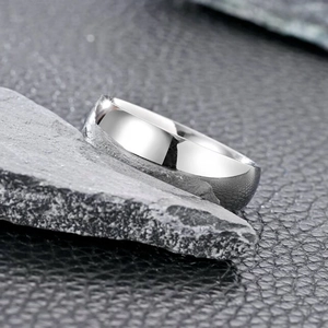 Macro shot of minimalist silver stainless steel ring on dark rock and leather