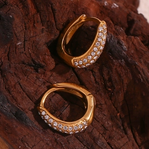 Macro view of gold mini pear-shaped earrings with pavé zircons on natural bark texture