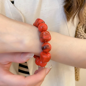 Gros plan d'un bracelet en acrylique rouge marbré avec perles carrées et rondes au poignet