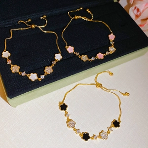Detail of adjustable gold-plated bolo bracelets with clover charms and zircon accents