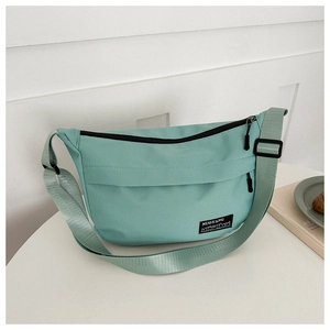 Detail of mint green oxford sports crossbody bag featuring black zipper and logo tag