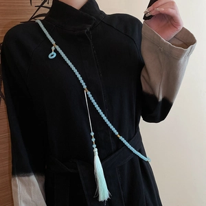 Detailed view of light blue beaded pendant with silk tassel on traditional Chinese dress