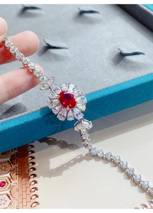 Dettaglio ravvicinato di un bracciale di lusso con gemma rossa e design floreale