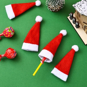 Close-up of mini red velvet Santa hats decorating lollipops on a festive green background