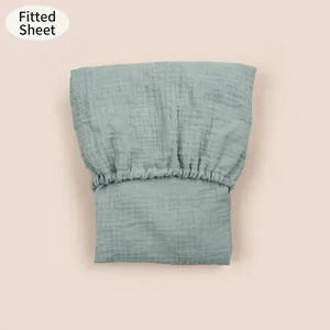 Detail of sage green cotton gauze fitted sheet showing elastic edges and crinkled texture
