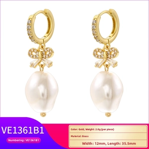 Detail of elegant brass bow earrings with drop baroque pearls and sparkling zircon stones