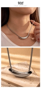 Detail of minimalist curved crescent pendant on a snake chain with silver mirror finish