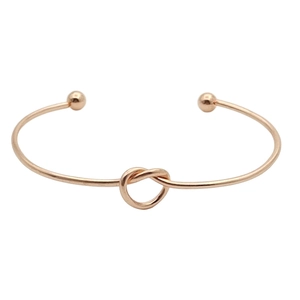 Minimalist rose gold knotted heart bangle with small sphere ends on white background