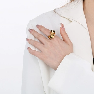 Vue détaillée d'une bague sculpturale dorée portée au doigt sous un éclairage pro