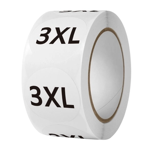 Close-up of round white adhesive clothing size labels with 3XL text on a roll