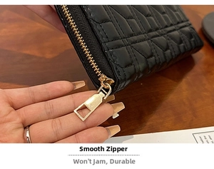 Close-up detail of smooth gold-tone zipper on quilted black long wallet for women