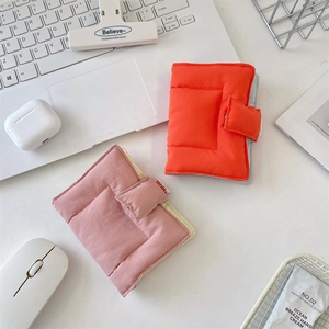 Quilted fabric binder covers in orange and pink with snap button closure on desk