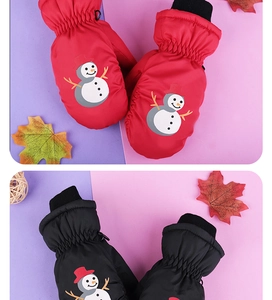 Close-up of waterproof children's ski mittens in red and black with cute snowman patterns