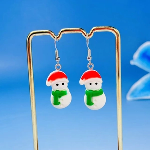Close-up of cute Christmas snowman earrings with red hat and green scarf on a gold stand