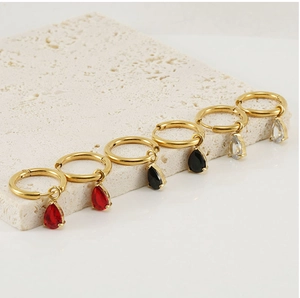 Detail of gold hoop earrings with teardrop zircon pendants in red, black and clear