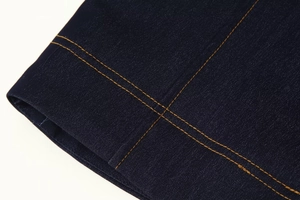 Gros plan du denim bleu foncé avec coutures contrastées orange sur la veste de mode