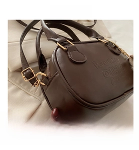Detailed close-up of dark brown leather handbag featuring embossed lettering and gold hardware
