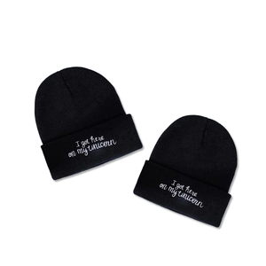 Two black knitted beanie hats with white embroidered text I got here on my unicorn phrase