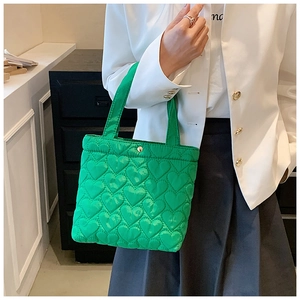 Detail view of a green tote bag featuring a 3D heart-quilted pattern and glossy finish