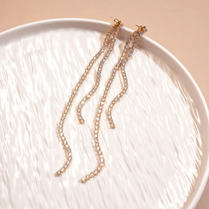 Close-up of elegant double long tassel earrings with sparkling cubic zirconia in gold