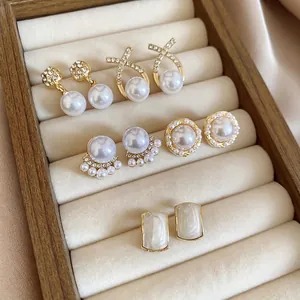 Elegant gold-tone earring set with white pearls and rhinestones on velvet display