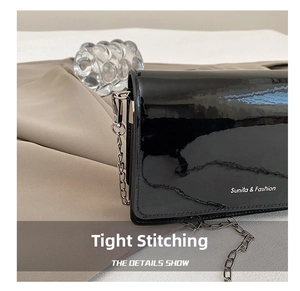 Detail showing high-quality stitching on black patent leather bag with silver chain