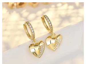 Macro shot of gold heart earrings with polished finish and micro-paved white zircons