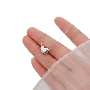Detailed view of the silver heart pendant with a polished finish held in hand