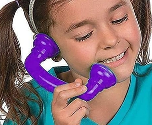 Smiling young girl using a purple toy telephone handset against a white background