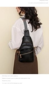 Model wearing black faux leather crossbody bag with striped strap on beige background