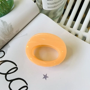 Detail of a minimalist oval claw clip in cream orange with a glossy resin finish