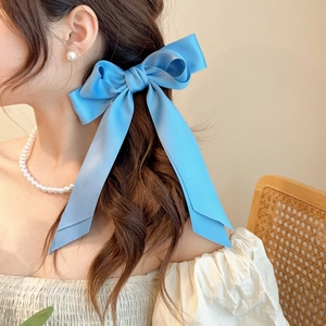 Light blue oversized satin bow hair clip with ribbons worn by a female model