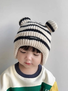 Close-up of baby knitted earflap hat with cute bear ears and striped pattern texture