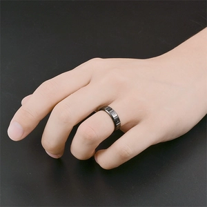 Close-up of matte black titanium steel ring with grooved design worn on hand