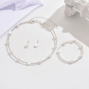 Detailed view of silver jewelry set with pearls and rhinestones on elegant white backdrop