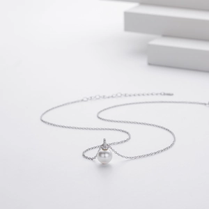 Macro detail of 925 sterling silver chain with a round white pearl and zircon pendant
