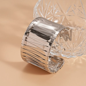 Detail of silver metallic wide cuff bracelet with multi-layer folded texture on glass