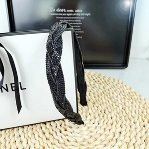 Detailed view of black braided headband with shimmering rhinestones on woven straw mat