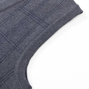 Detailed close-up of dark grey-blue knit vest featuring textured plaid jacquard pattern