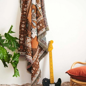 Detail of bohemian knit throw featuring geometric patterns and caramel fringe texture