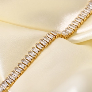 Dettaglio di lussuoso bracciale in oro con zirconi rettangolari su seta pregiata